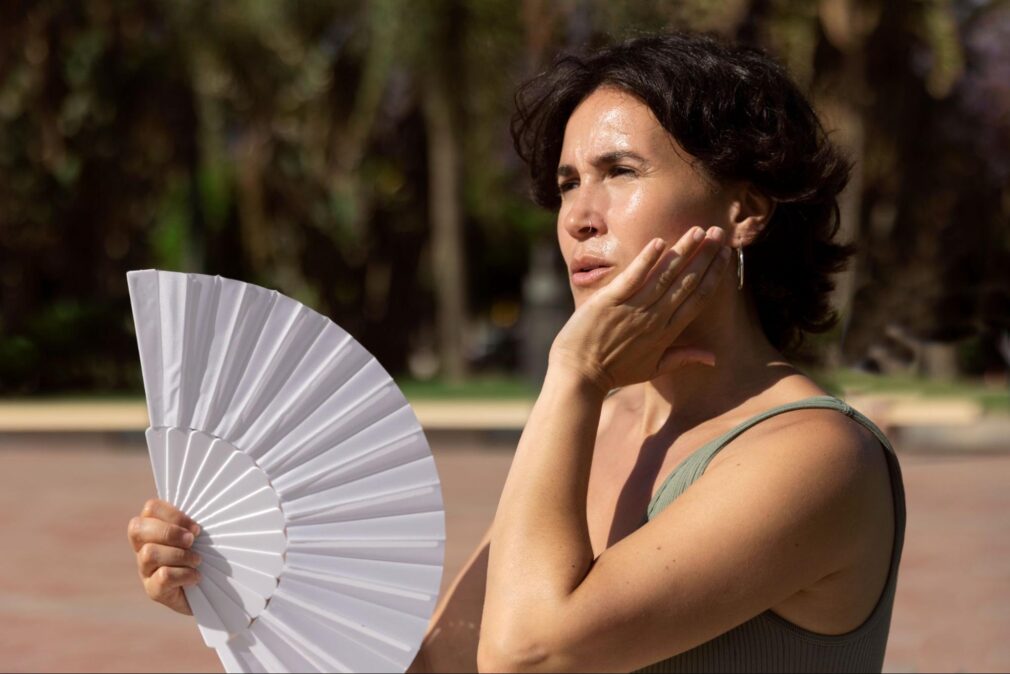 A woman with a fan on a hot weather