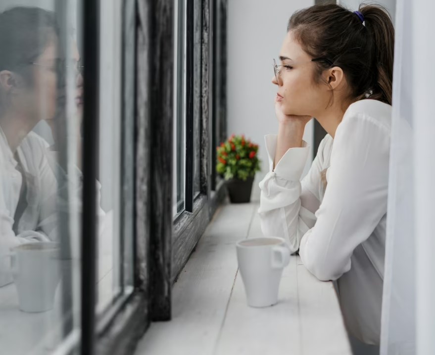 a side view of a businesswoman wearing a white shirt and looking outside a window