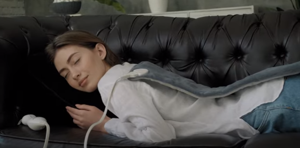 a woman sleeping on a couch with a Heating Pad