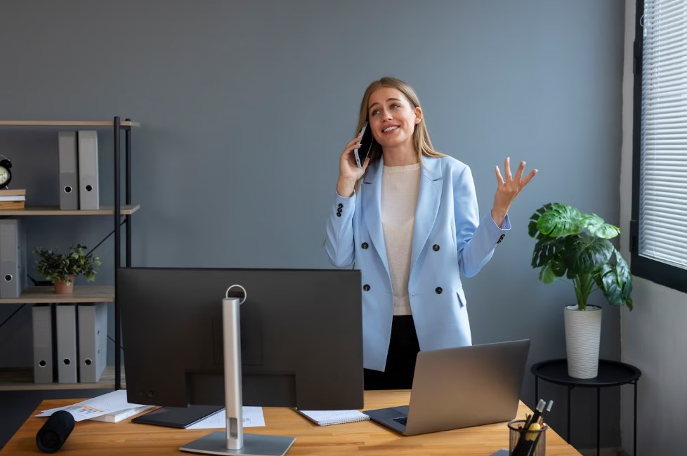 a young businesswoman in a blue jacket talking on the phone and smiling in the office