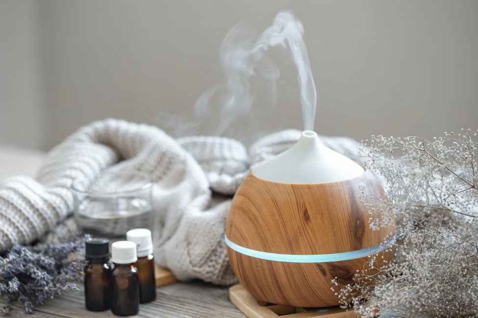 a modern aroma oil diffuser or a humidifier on a wooden surface with a knitted element a glass of water and small jars