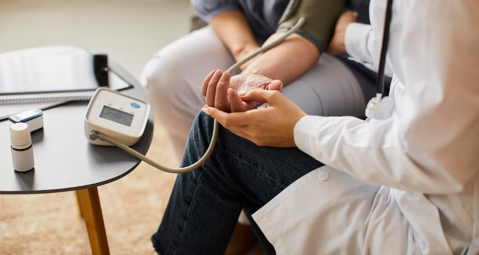 a female doctor checking an elder patient’s blood pressure near the coffee table