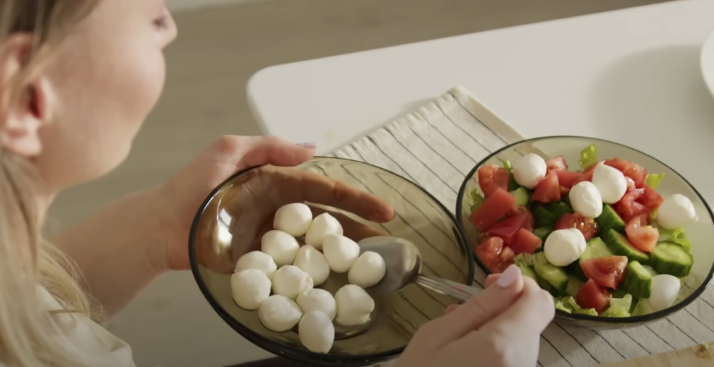 A woman enjoying a meal with two bowls filled with vegetables