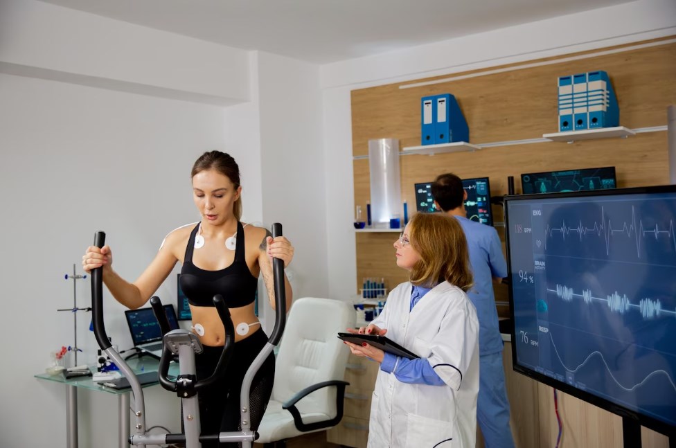 a female athlete training on an exercise bike while a doctor analyzes her health condition