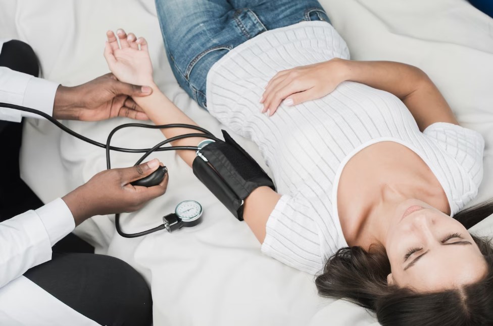 a black medic measuring pressure of a white woman on a bed