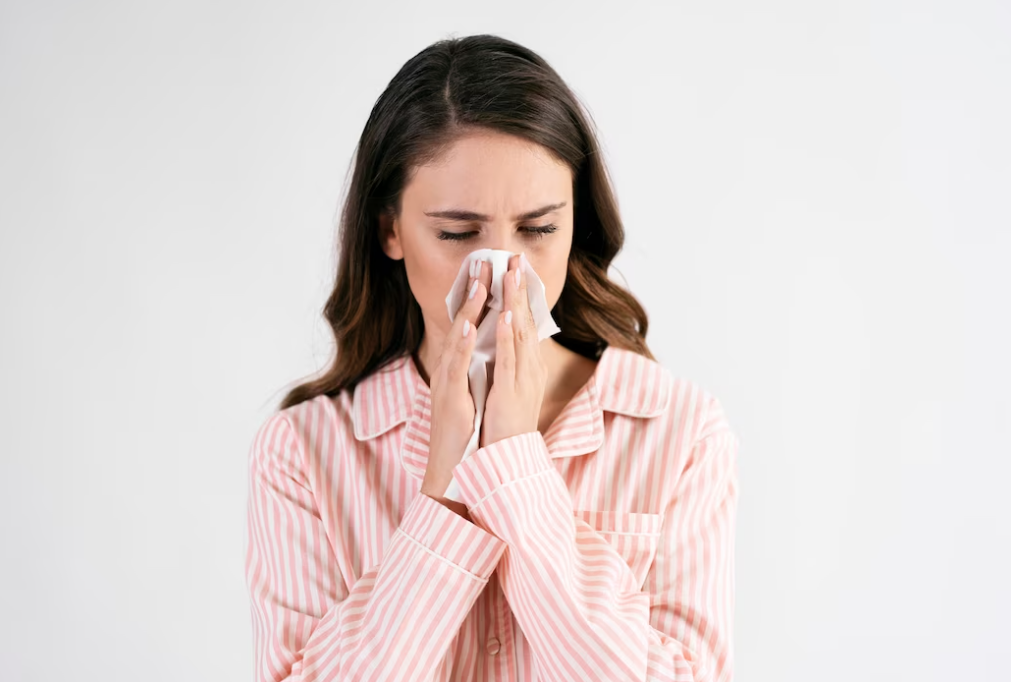 woman in striped pink pajama wipes her nose with the napkins