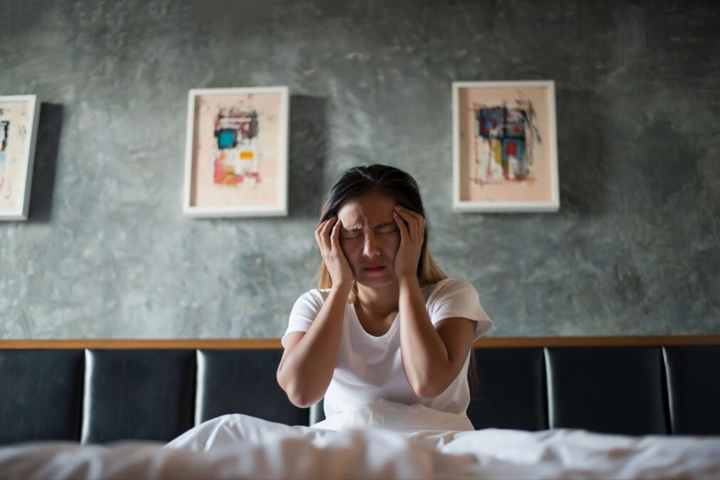 Woman with headache her hand holding head on the bed