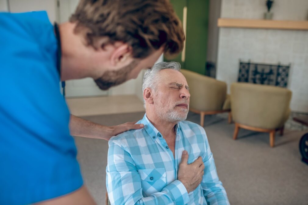 Doctor bending towards a man with a chest pain